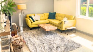 A living room with a yellow sofa, a wooden coffee table, a grey shaggy rug, a floor lamp, and a window with a view of greenery. - Chichester House I Secure Garden I Parking I Close to Goodwood (Chichester)