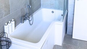 A bathroom with a bathtub, shower, and a glass-enclosed shower area. - Chichester House I Secure Garden I Parking I Close to Goodwood (Chichester)