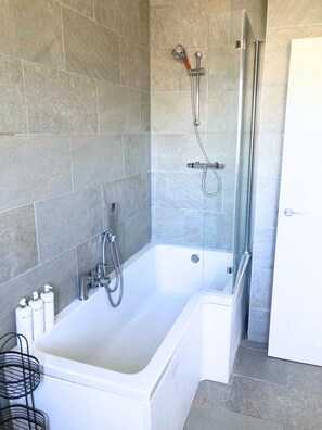 Un baño con bañera, ducha y zona de ducha con cerramiento de vidrio.