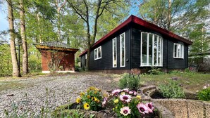 Una casa con techo rojo, rodeada de árboles y un camino de grava.