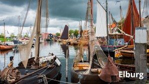Un port de plaisance où sont amarrés différents types de bateaux, notamment des voiliers et des bateaux à moteur, sous un ciel nuageux.