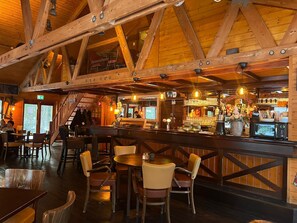 A rustic interior with wooden beams, a bar area, and seating arrangements.