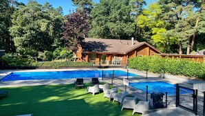 Una piscina con un edificio de madera al fondo, rodeada de árboles.