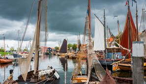 Uma marina com vários barcos atracados, incluindo veleiros e barcos a motor, sob um céu nublado.