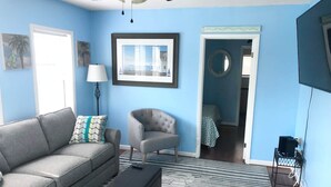 A living room with a grey sofa, a grey armchair, a striped rug, and a framed picture on the wall.