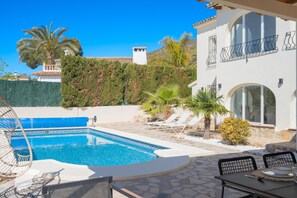 Relax by the serene pool surrounded by a patio and lush greenery.