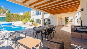 Eine Außenpatio mit Pool, Essbereich und Grillplatz.