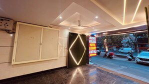 Un hall d'hôtel au design moderne, avec un grand miroir, un panneau lumineux publicitaire pour les chambres et une vue sur la rue.