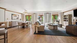 A spacious living room with a wooden floor, a sofa, a coffee table, and a dining area with a table and chairs. - The Aspen Mountain Residences 49AB - 2 Bedroom Residence (Aspen)