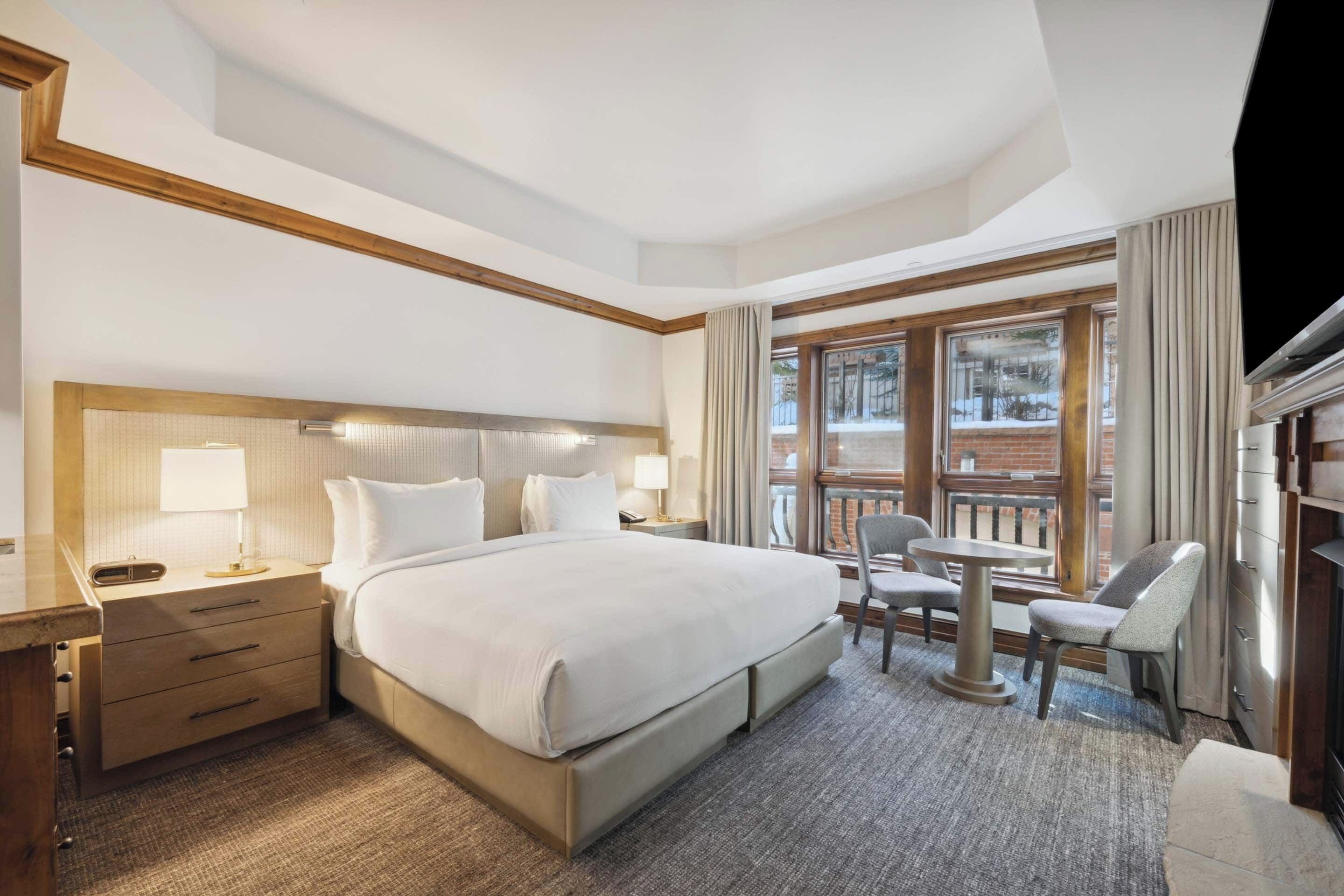 Une chambre d’hôtel avec un grand lit, des tables de chevet, un bureau, une chaise et un balcon avec vue.