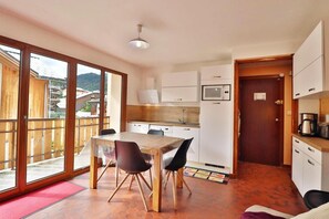 A kitchen with a dining table, chairs, a microwave, and a refrigerator.