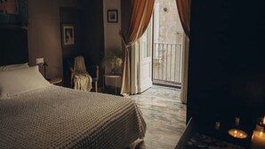 A hotel room with a large bed, a chair, a small table, and a balcony with a railing. - Room in the historic center of naples donna vittoria  (Napoli)