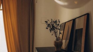 A room with a window covered by curtains, a vase with flowers on a table, and framed pictures on the wall. - Room in the historic center of naples donna vittoria  (Napoli)