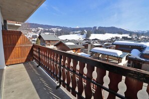 Un balcón con vista a un pueblo cubierto de nieve y montañas.