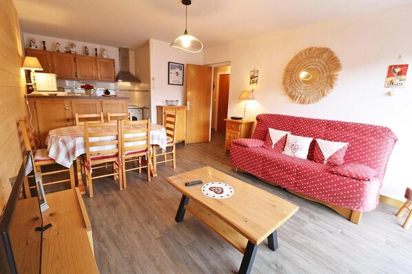 Una sala de estar acogedora con un sofá rojo estampado de lunares, una mesa de comedor de madera y sillas.