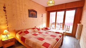 A wooden room with two beds, a nightstand, a lamp, a window with a view, and a wall-mounted picture. - 1st floor, balcony, tv, 45m², Les Gets (Les Gets)