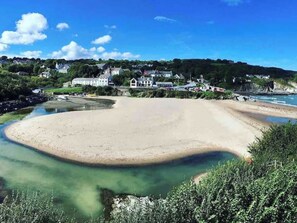 A coastal landscape with a sandy beach, clear water, and houses in the background. - The Apartment - UK47181 (Tanygroes, near Llangrannog)