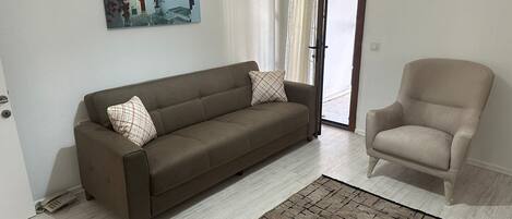 Un salon avec un canapé, un fauteuil et un tapis.