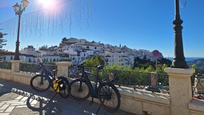 A bicycle parked on a paved area with a view of a white building complex in the background. - Casa Paqui in Frigiliana (Frigiliana)