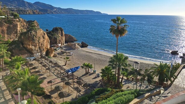 A beach with umbrellas, palm trees, and a view of the sea and mountains. - Casa Paqui in Frigiliana (Frigiliana)