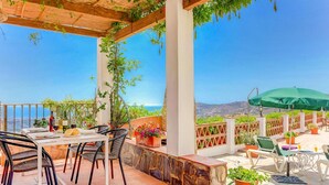 An outdoor patio with a table set for dining, surrounded by chairs and potted plants. - Casa Paqui in Frigiliana (Frigiliana)