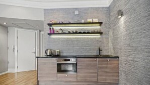 Eine moderne Küche mit Backofen, einer Arbeitsplatte aus Edelstahl und einer grauen, strukturierten Spritzschutzwand.