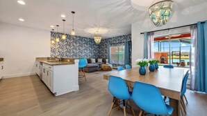 A modern kitchen with white cabinets, a wooden island, and blue chairs. - Disney Retreat: Pool, Themed Rooms, Pets Welcome! (Kissimmee)