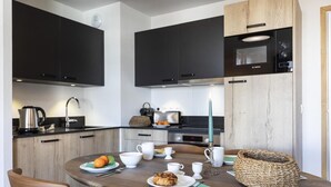 Une cuisine moderne avec des meubles de couleur sombre, un four à micro-ondes et une machine à café.