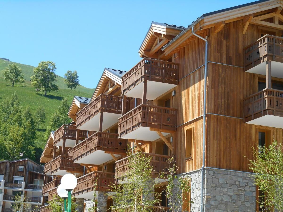 Ein mehrstöckiges Holzhaus mit Balkonen, eingebettet in eine Hanglage.