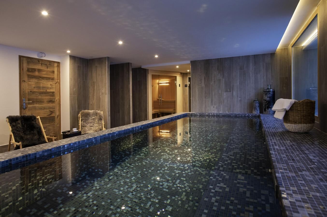 Una piscina interior moderna con suelo de baldosas y puerta de madera.