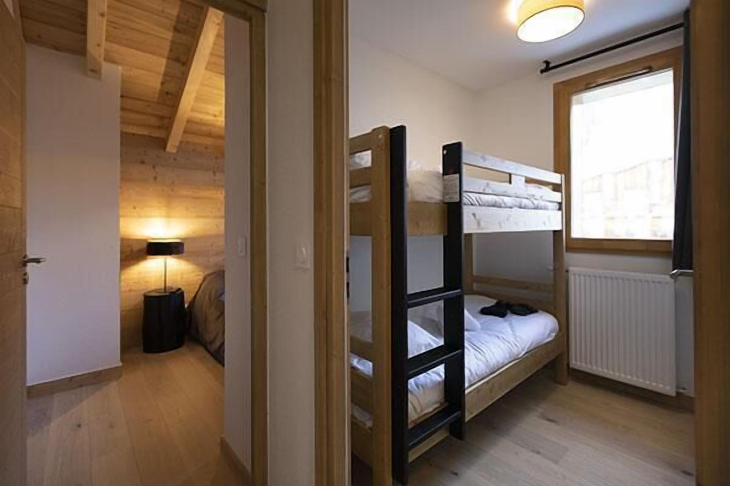A bunk bed room with a window, a radiator, and a lamp.