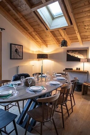 A dining area with a high wooden ceiling, a skylight, and a table set for four with chairs. - Wifi, fitness, sauna, hammam, terrace, balcony, parking, tv, ski locker, 62-69m², Les 2 Alpes (Les Deux Alpes)