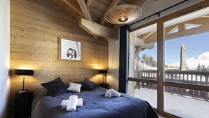 Camera da letto con un letto grande, pareti in legno, un quadro incorniciato e vista su un paesaggio innevato.
