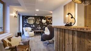 Een kapsalon interieur met twee witte fauteuils, een houten receptiebalie en een spiegel.