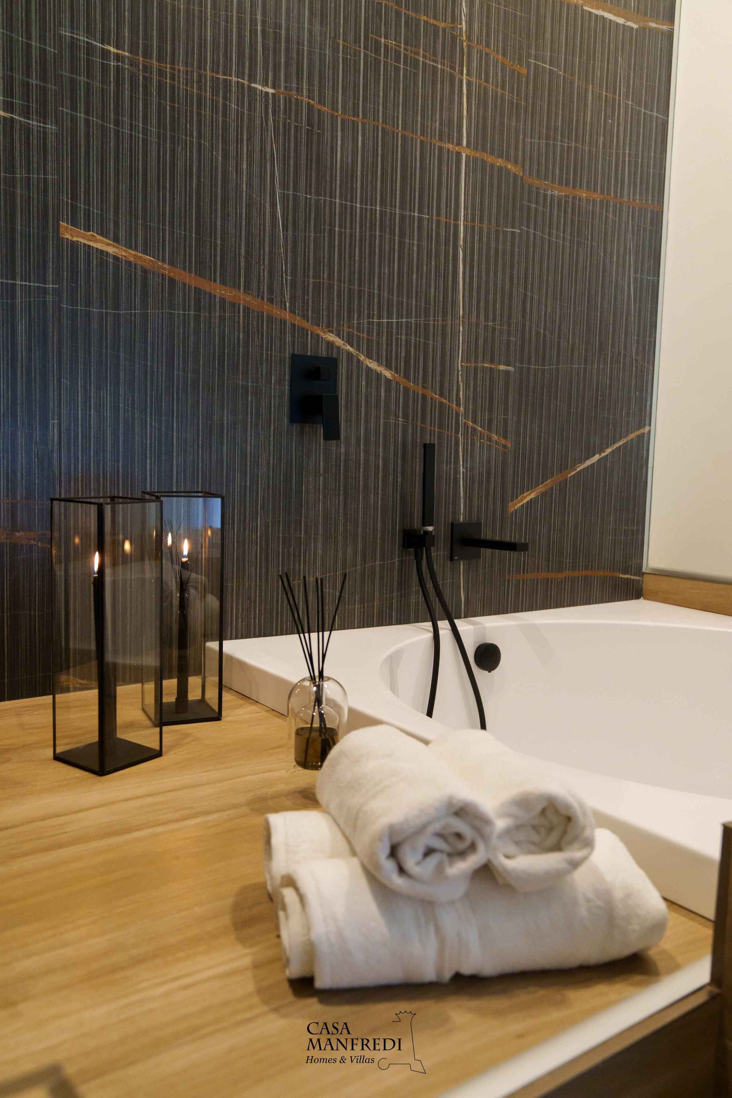 Un baño moderno con una bañera grande, un tocador de madera y un perchero para toallas en la pared.