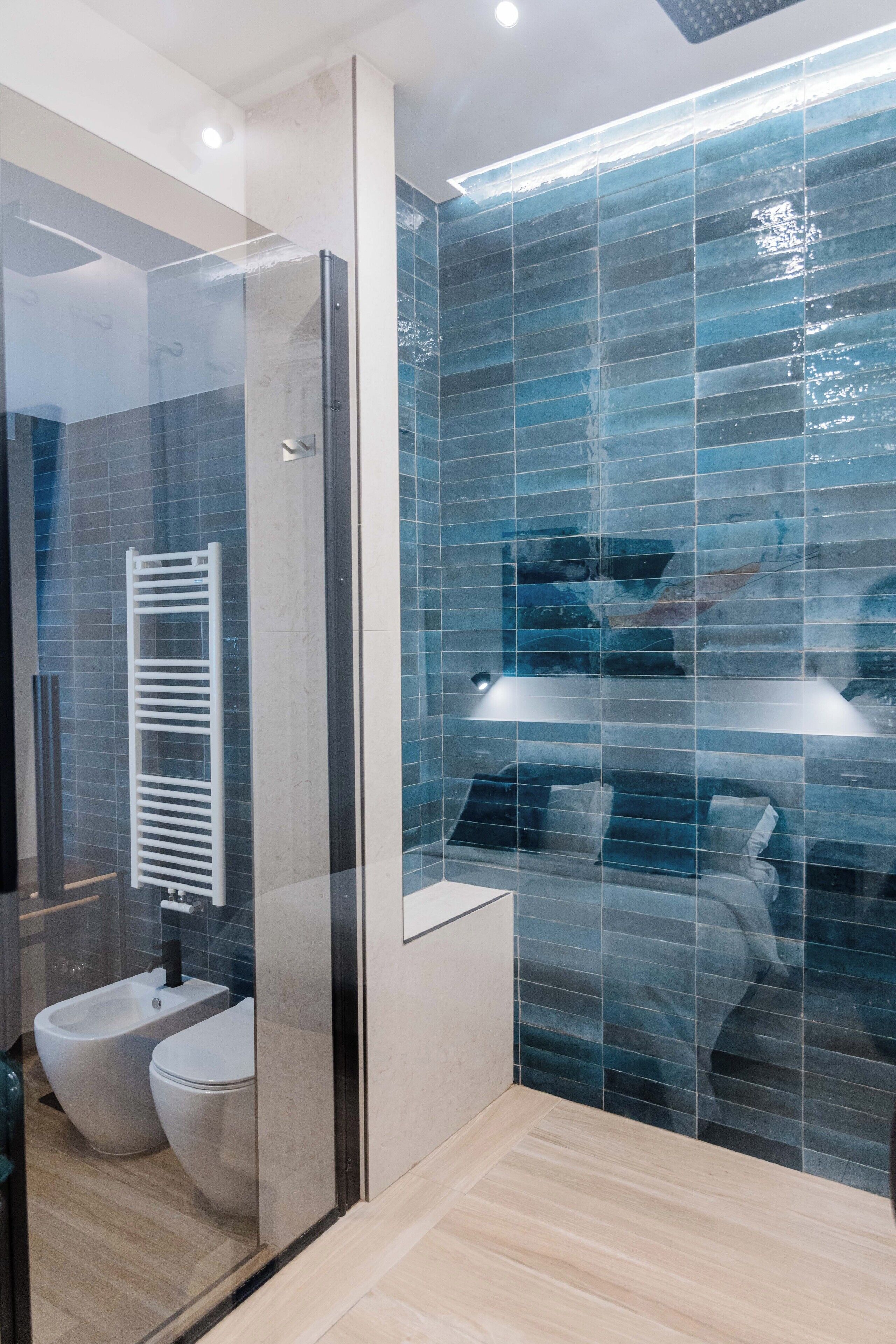 A modern bathroom with a glass shower enclosure, a bidet, and a toilet.