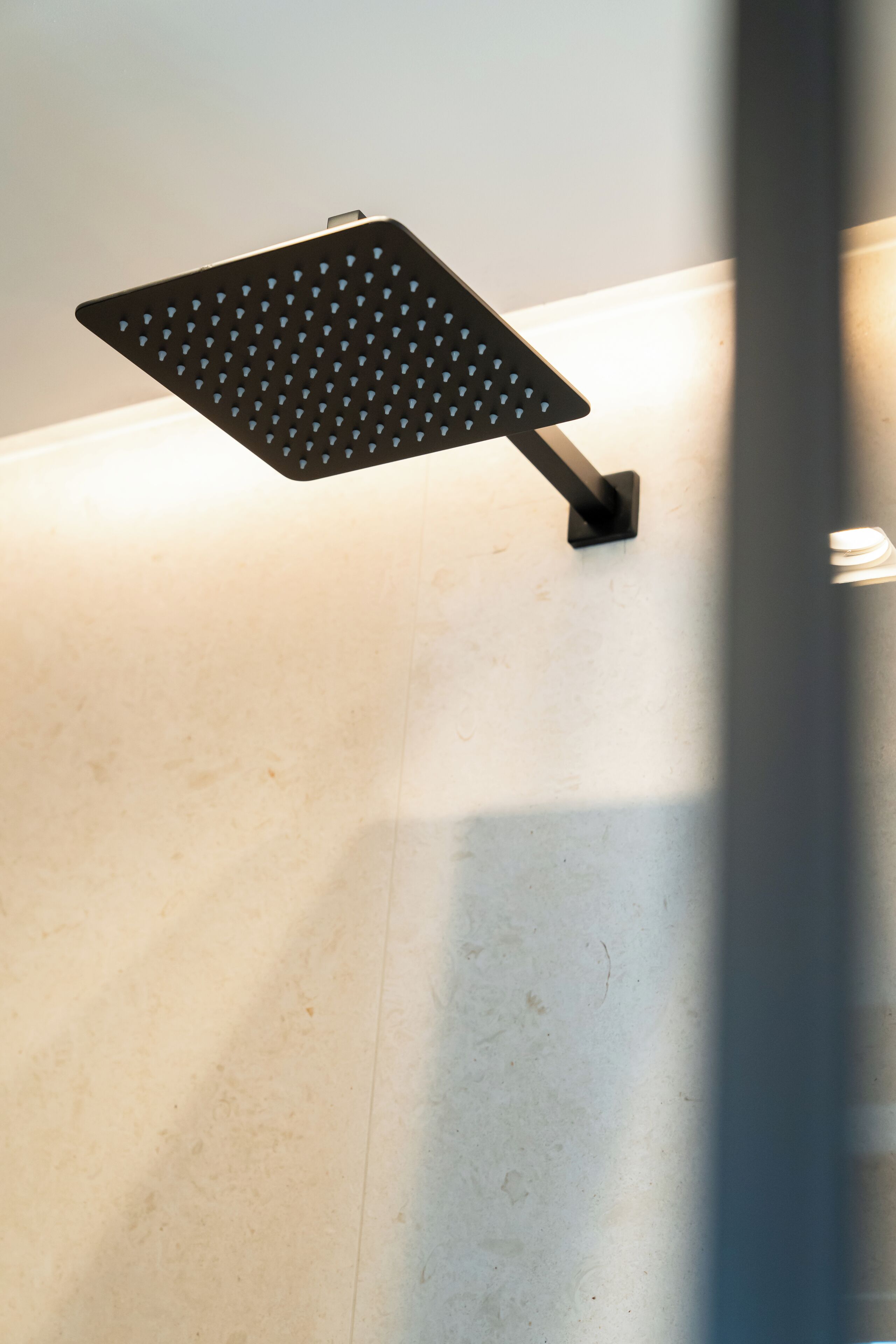 A showerhead mounted on a wall with a tiled floor.
