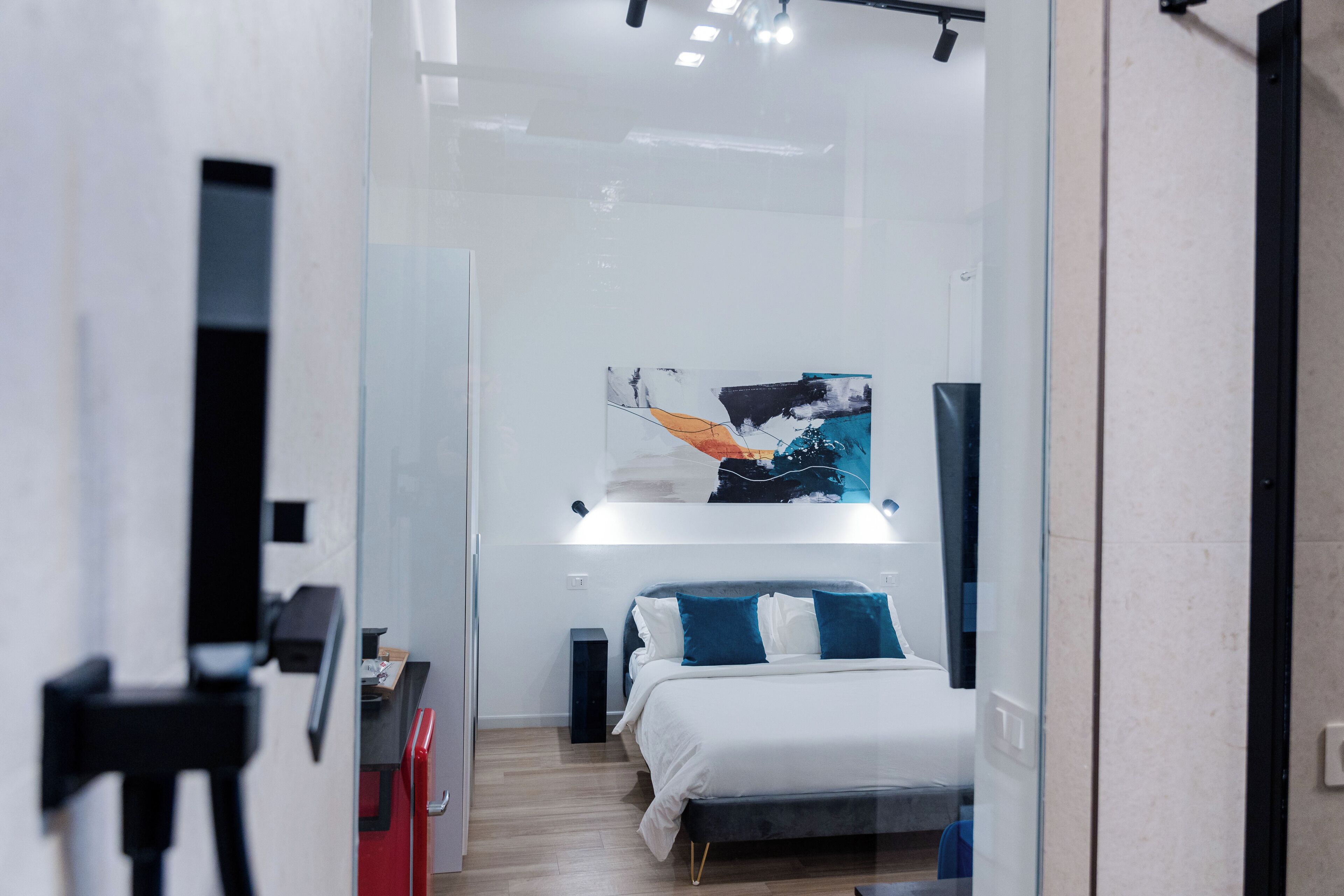 Ein modernes Hotelzimmer mit Bett, Nachttischen, einem Gemälde und einer Glastrennwand.