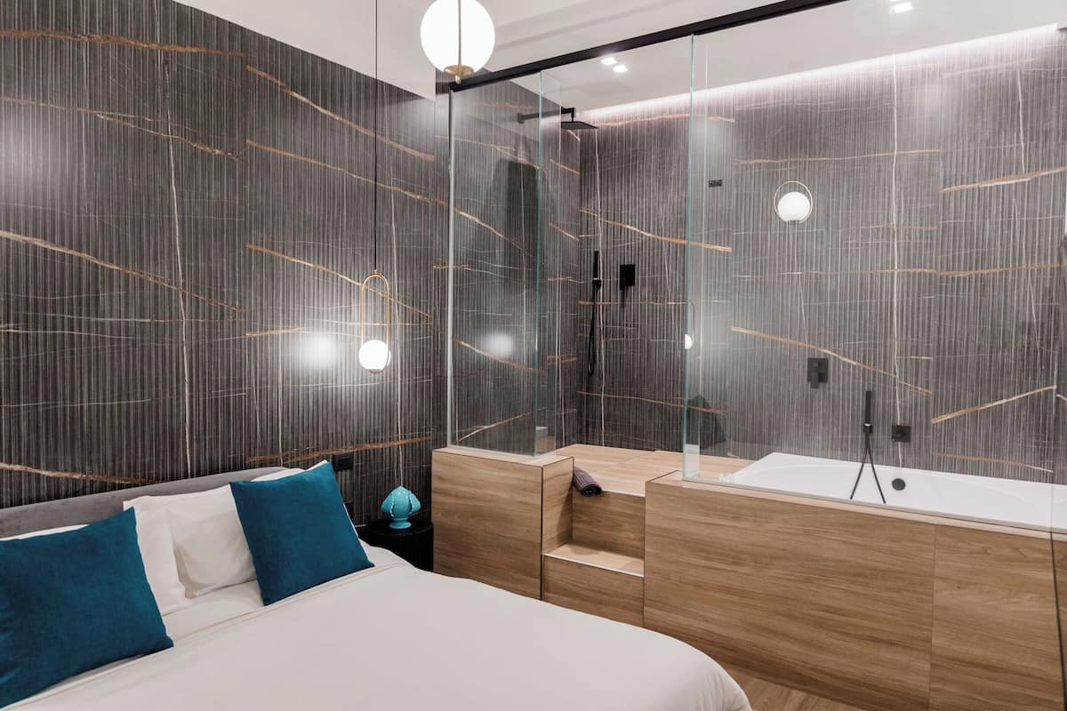 Una habitación de hotel moderna con una cama grande, un tocador de madera y un box de ducha de vidrio.