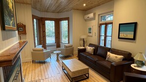 Een ruime woonkamer met houten vloeren, een open haard, een bank en een bijzettafeltje.