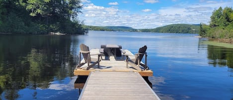 Une jetée en bois s’avançant dans une étendue d’eau calme, avec une table de pique-nique et des chaises.