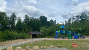 Un parque infantil con un pabellón de madera, columpios y un tobogán.