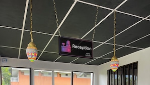 A reception desk with a laptop, a reception sign, and a view of the outside. - Asha Hostel (La Fortuna)