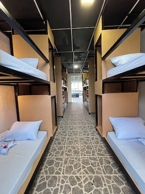 A train compartment with bunk beds, a tiled floor, and a central aisle leading to a window. - Asha Hostel (La Fortuna)