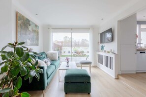 Un salon moderne avec un canapé vert, une table basse et une grande fenêtre.