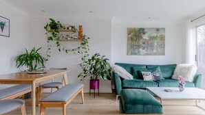 Ett modernt vardagsrum med ett matbord i trä, bänkar, en turkosfärgad soffa och ett soffbord.