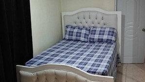 Un dormitorio con cama, una puerta y un equipo de aire acondicionado.