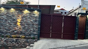 Una entrada protegida por un muro de piedra y una reja metálica.
