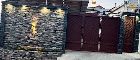 A gated entrance with a stone wall and a metal gate.