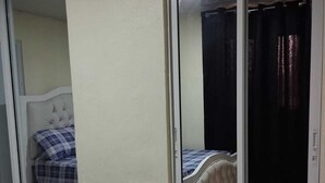 Un dormitorio con cama, puerta corrediza de vidrio y suelo de baldosas.